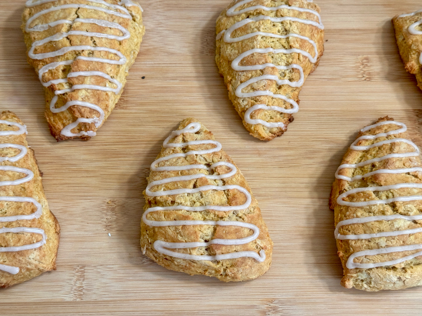 Pumpkin spice scones with cinnamon icing on a wooden surface