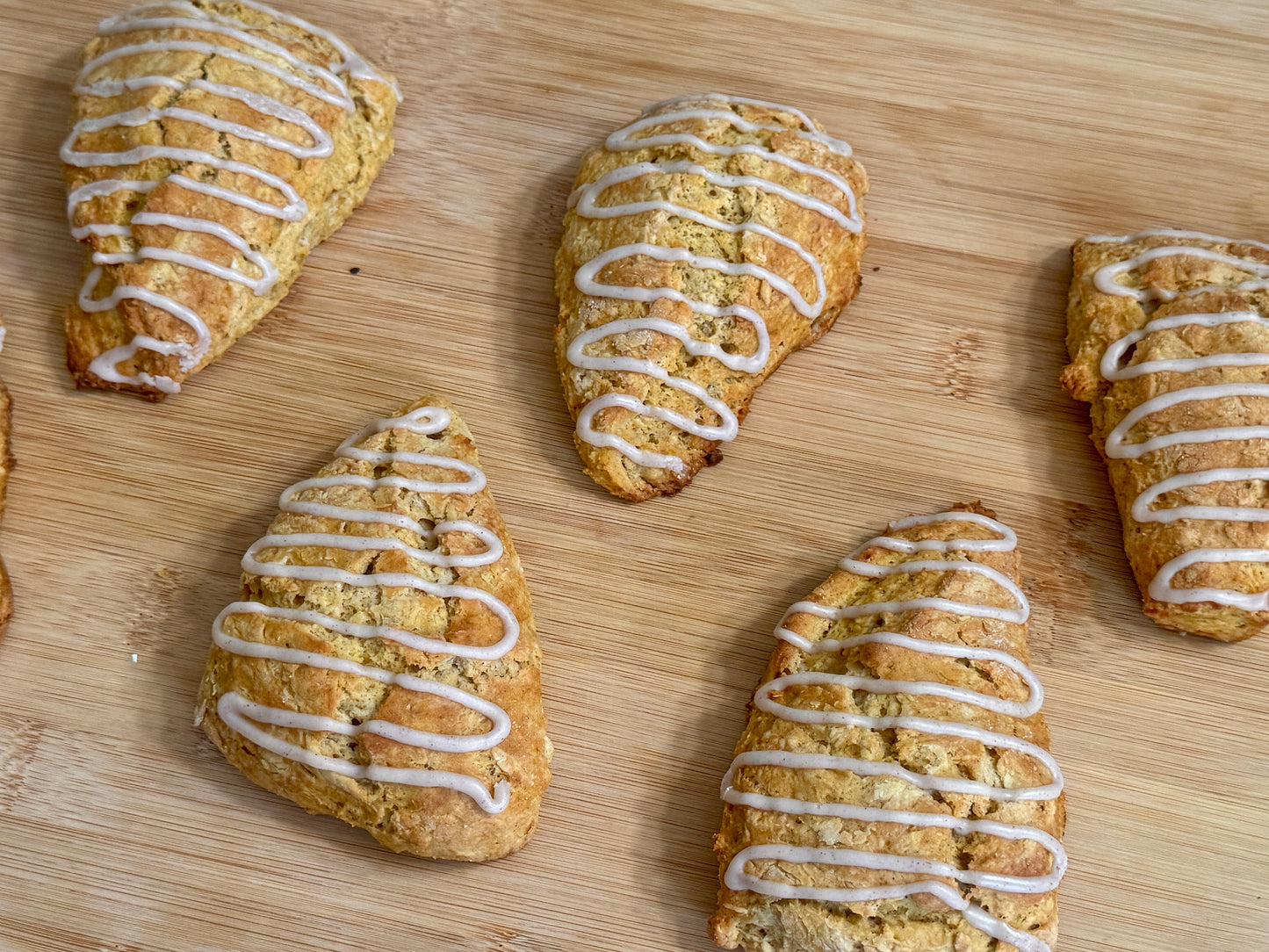 Pumpkin scones with cinnamon icing on a wooden surface