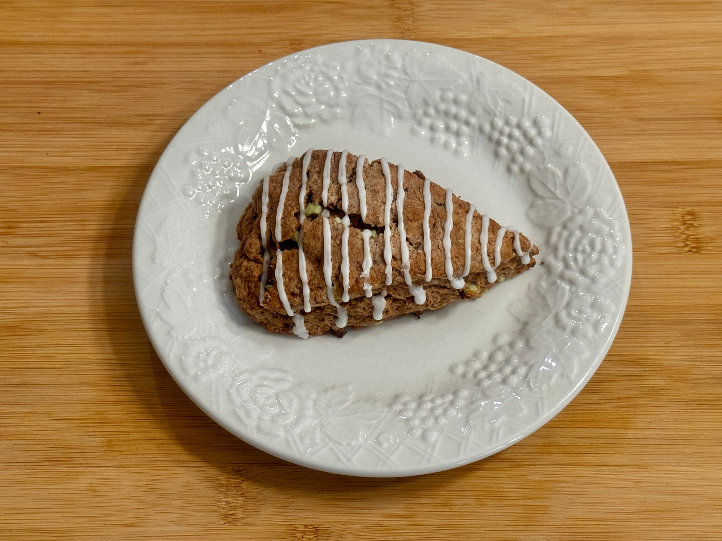 Peppermint Mocha Scone with icing on a decorative white plate on a wooden surface