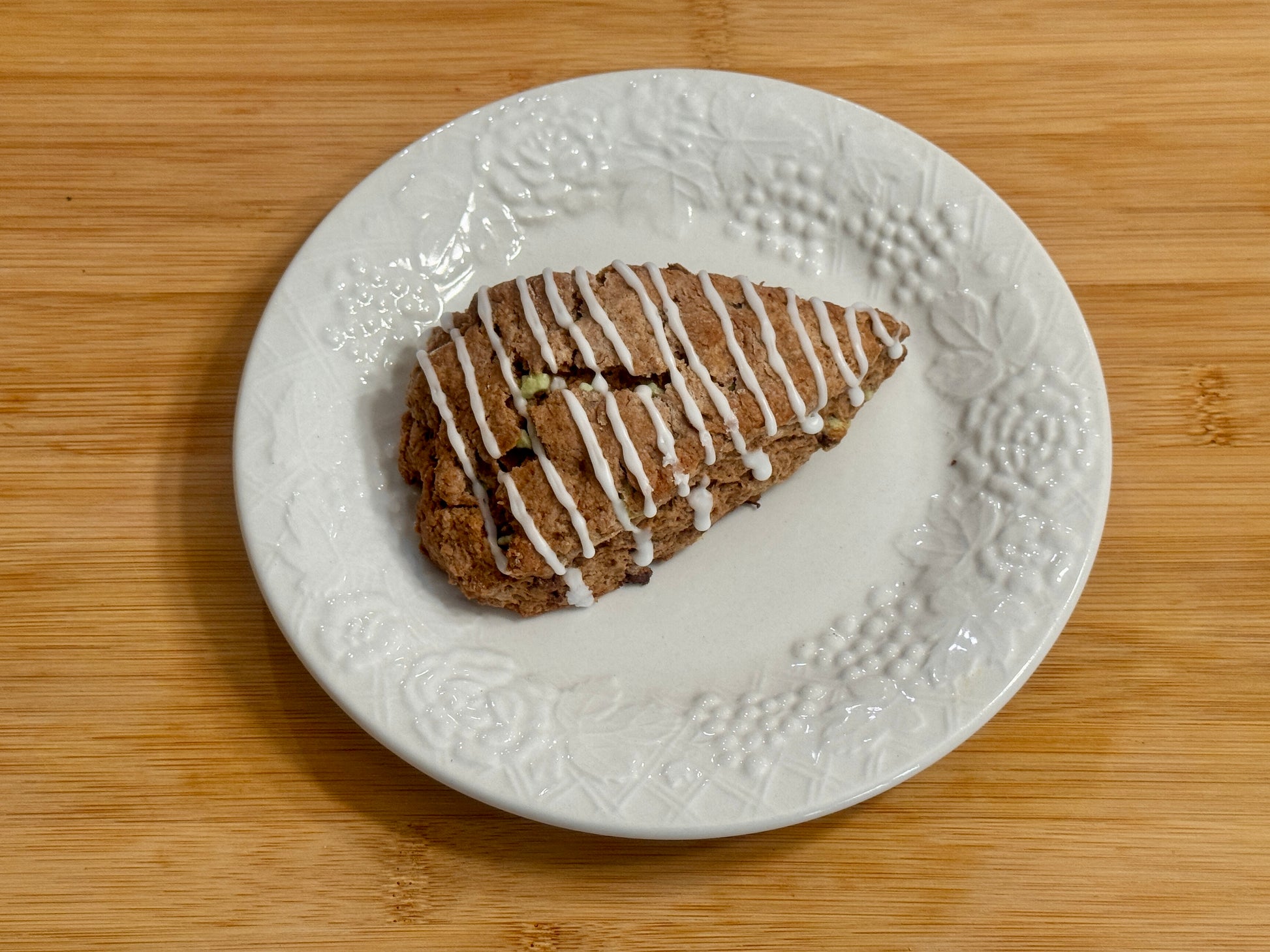 Chocolate Peppermint Scone with white drizzle on a white plate on a wooden surface
