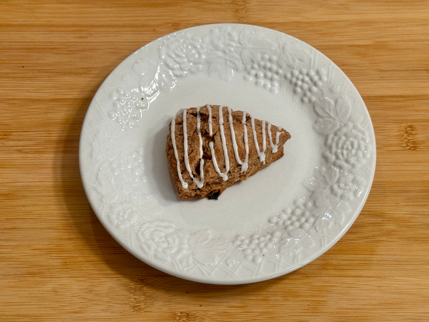 peppermint mocha mini scone with white drizzle on a decorative white plate on a wooden surface