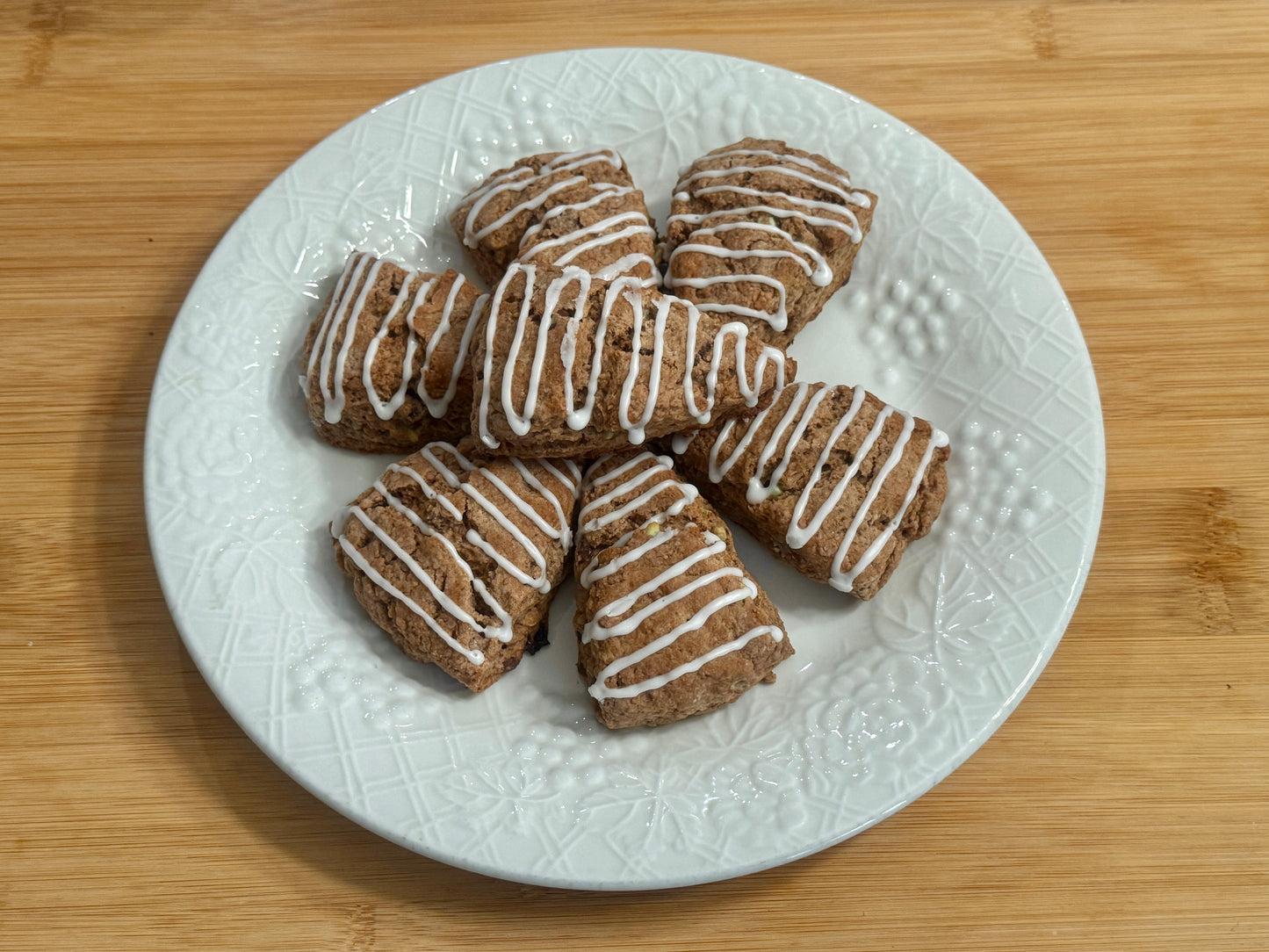 Plate of peppermint mocha scones with mint drizzle on a wooden surface