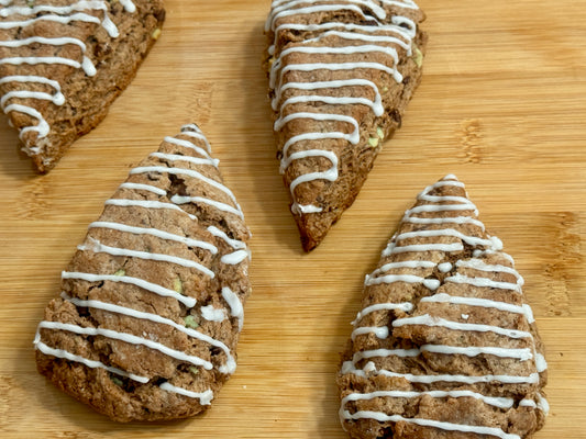 four peppermint chocolate scones with mint drizzle on a wooden surface