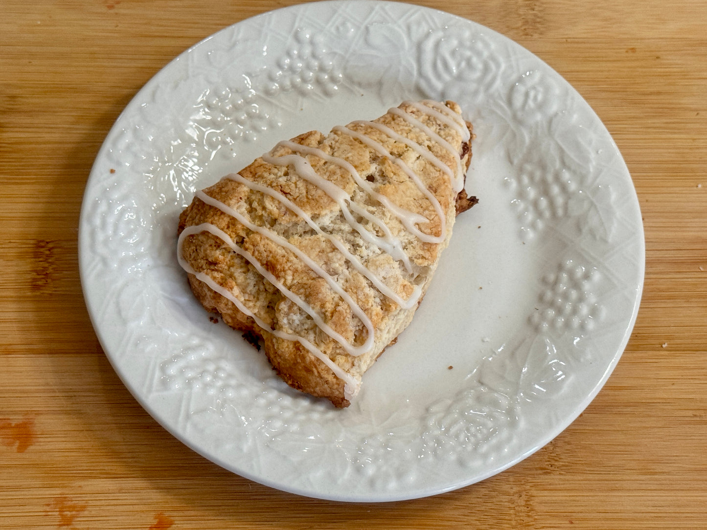 Strawberry Scone with icing on a white plate on a wooden surface
