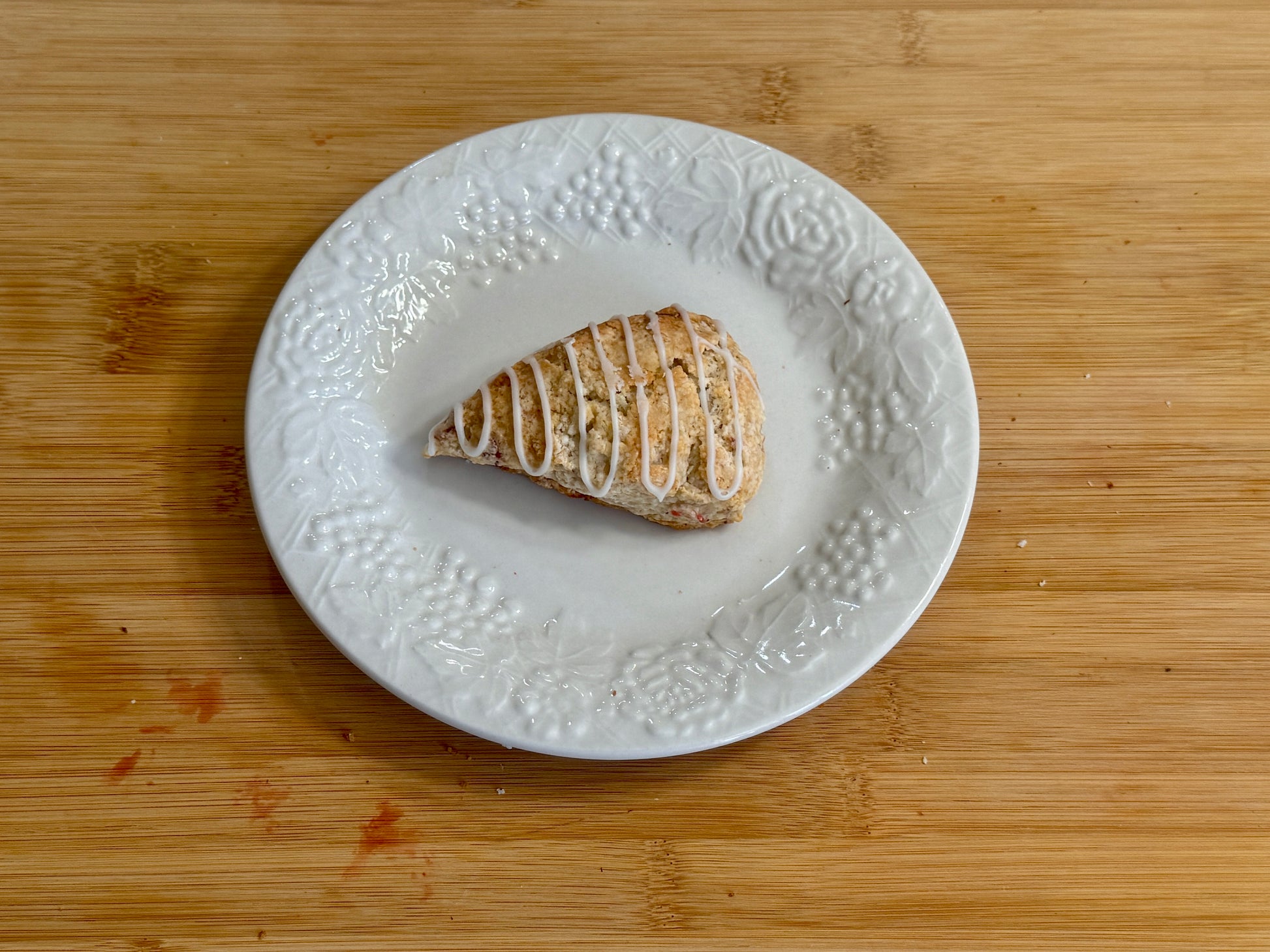 Strawberry mini scone on a decorative white plate on a wooden surface